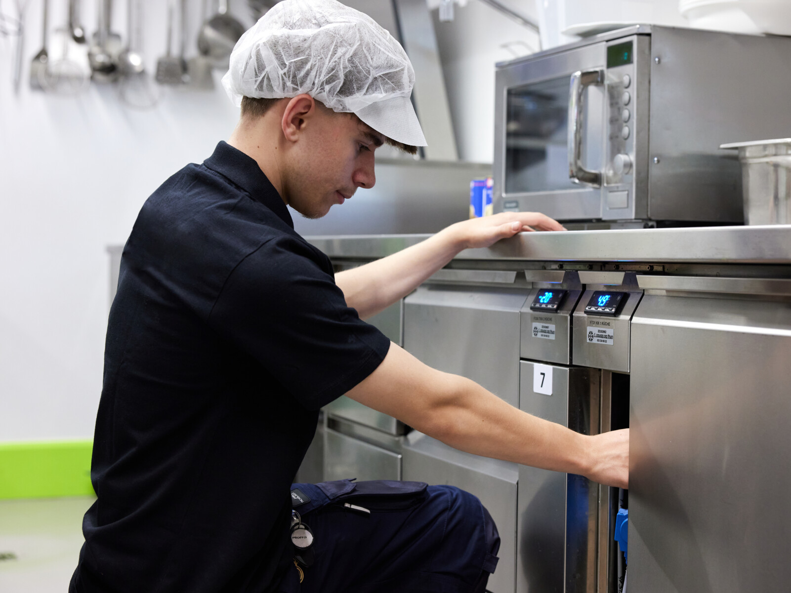 Auszubildender Kältesystem-Monteur der Zaugg AG bei der Wartung einer Kühlanlage in einer Grossküche. - Ausbildung Kältetechnik